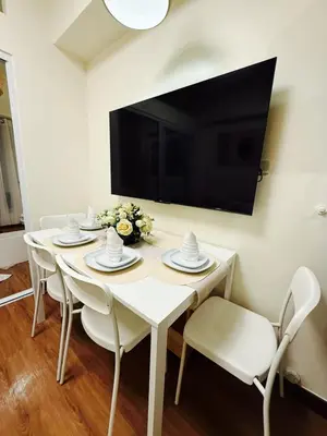 a white dining room table with white chairs and a flat screen tv at The Camden Place Aesthetic Elegant Condo Unit 15 in Manila