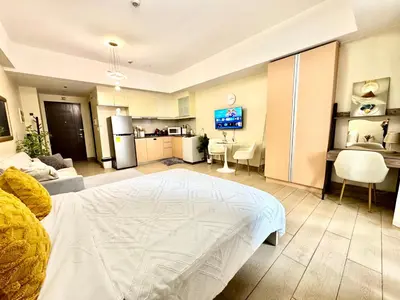 a living room with a bed and a kitchen at Cozy Apartment in Venice Luxury Residences BGC in Manila