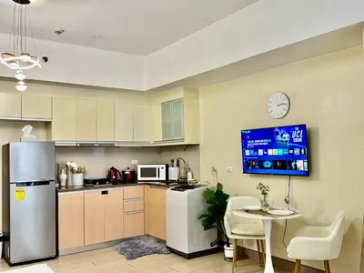 a kitchen with a refrigerator and a table and a tv at Cozy Apartment in Venice Luxury Residences BGC in Manila