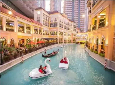 two people are riding on swan boats in a canal at Cozy Apartment in Venice Luxury Residences BGC in Manila