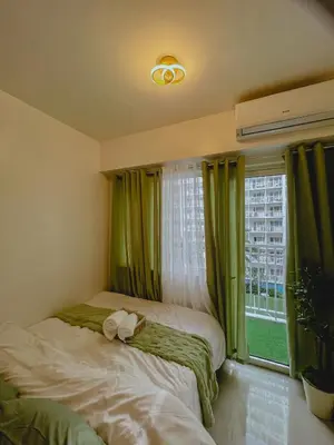 two beds in a room with green curtains and a window at Staycation near Mall of Asia in Manila