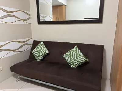 a brown couch with two pillows sitting under a mirror at Ate Aby's Place 338 in Manila
