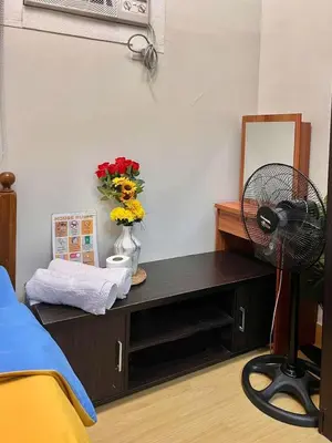 a room with a desk with a fan and flowers at Vacation Home MOLUAN in Manila
