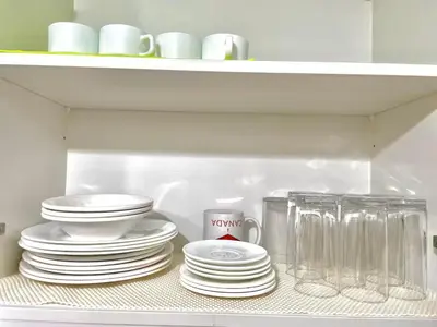 a shelf with plates and cups and a stack of dishes at Manhattan Plaza Suite 1BR with City View, Netflix and Pool Access in Manila
