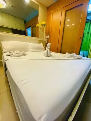 a large white bed in a room with towels on it at 232 1br big balcony 2 queen size 1-sofa bed 1single extra mattress in Manila