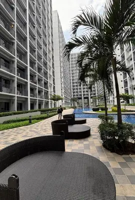 a courtyard in a large building with tables and palm trees at R Cabin - Shore Residences in Manila