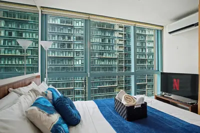 a person laying on a bed in front of a large window at BGC High Rise, Uptown Mall Link, 5G WiFi, Pool, Ste 19 in Manila