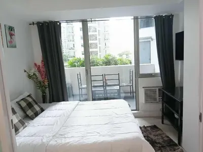 a bedroom with a large bed and a large window at Azure Residences 1 Bedroom with Wide Balcony in Manila
