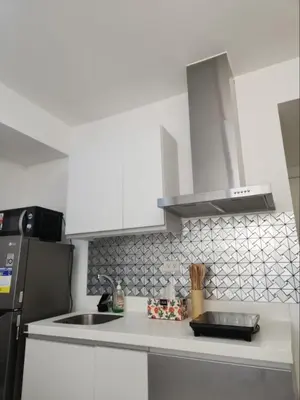 a kitchen with white cabinets and a sink and a refrigerator at Azure Residences 1 Bedroom with Wide Balcony in Manila