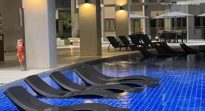 a swimming pool with black lounge chairs in a building at Cozy Family and Group-Friendly Private 2 Bedroom with Coffee Bar and Fast Wifi at S Residences Mall of Asia in Manila