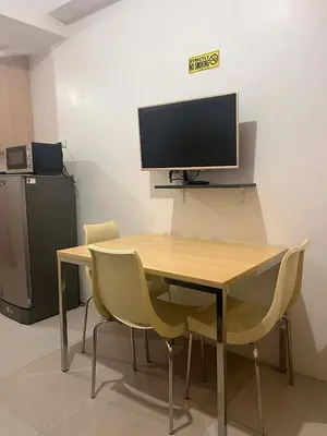 a desk with chairs and a computer monitor on a wall at 1 BR Boni LIGHT Condo WIFI Netflix Pool Balcony in Manila