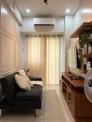 a living room with a black couch and a television at Near NAIA Mediterranean Cozy Home with Netflix in Manila
