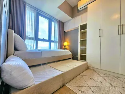 a bedroom with two beds and a window at Uptown BGC Residences by ChiKat in Manila