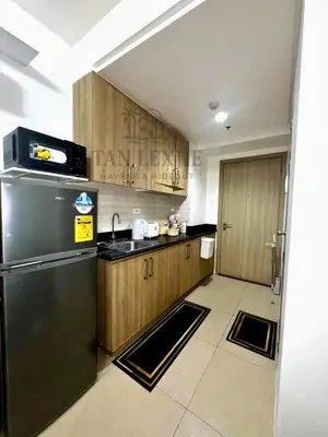 a kitchen with a black refrigerator and wooden cabinets at Shore Residences by Tan LexJie in Manila