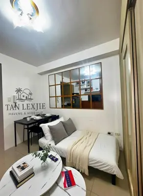 a living room with a bed and a table at Shore Residences by Tan LexJie in Manila