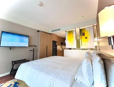 a bedroom with a white bed and a flat screen tv at Hotel Residences - Novotel Suites Manila at Acqua in Manila