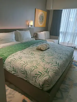 a large bed in a hotel room with a phone on it at Cleo Suites at Novotel Hotel Residences near Makati in Manila