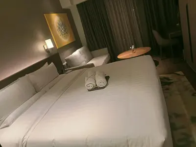 a bedroom with a large white bed with two slippers at Cleo Suites at Novotel Hotel Residences near Makati in Manila