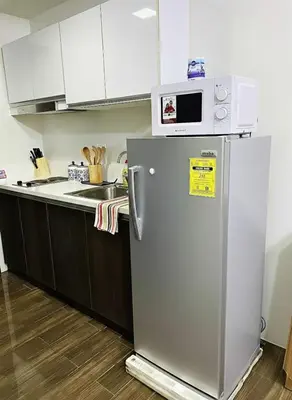 a microwave on top of a refrigerator in a kitchen at Air Residences 28F Balcony WiFi Netflix in Manila