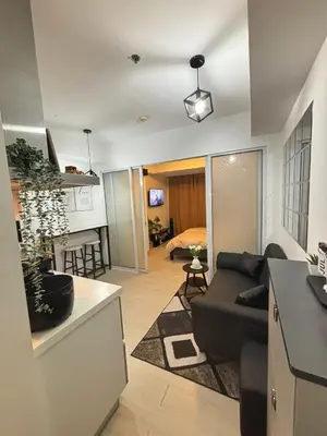 a living room with a black couch and a kitchen at Condotels SMB West Road in Manila