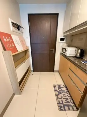 a small kitchen with a brown door and a counter at One Bedroom with Netflix at Uptown Residences, BGC, Taguig in Manila