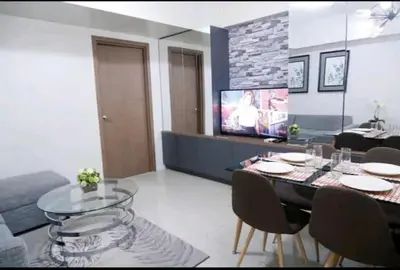a living room with a dining table and a tv at 5A Southwing in Manila