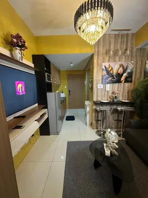a living room with a large television and a chandelier at David's Cozy Home in Manila