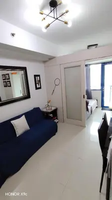 a living room with a blue couch and a bedroom at Moa SEA RESIDENCE condotel in Manila