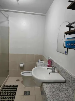 a white bathroom with a sink and a shower at Condotels by San Antonio in Manila