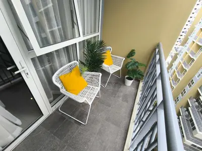 a balcony with two chairs with yellow pillows on it at Comfortable and Relaxing 1BR Unit in Manila