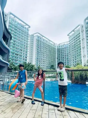 three children standing in front of a pool with buildings at Vacation Home by Star in Manila