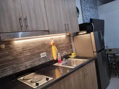 a kitchen with a sink and a refrigerator at Shore Residences at Mall Of Asia Complex - by Staycation Empire in Manila
