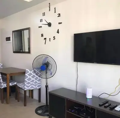 a living room with a wall clock and a fan at A Home Away From Home in Manila