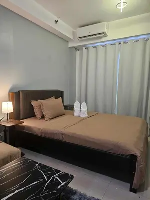 a bedroom with a bed and a window with a air conditioner at Shore Residences Sm mall of asia Marc in Manila