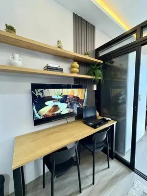 a desk with a laptop and a television on a wall at Cozy Sunset Condo Thompson Stay in Manila