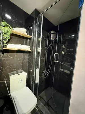 a bathroom with a toilet and a glass shower at Cozy Sunset Condo Thompson Stay in Manila
