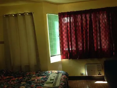 a bedroom with a bed and a window with red curtains at Studio Condominium near the US Embassy in Manila in Manila
