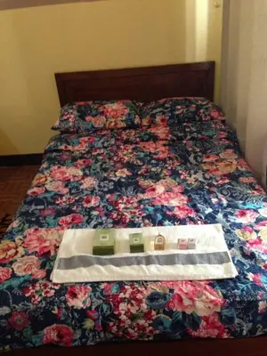 a bed with a floral comforter with a dress on it at Studio Condominium near the US Embassy in Manila in Manila