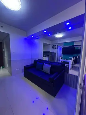 a living room with a blue couch and a kitchen at Shell Residences Mall of asia Pham in Manila