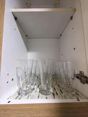 a row of empty glasses sitting on a shelf at Shell Residences Mall of asia Pham in Manila