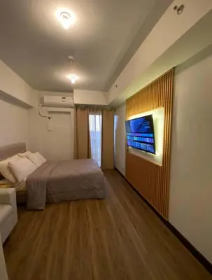 a bedroom with a bed and a tv on a wall at One br cozy resort style condo sunset view balcony Robinson Las Pinas in Manila