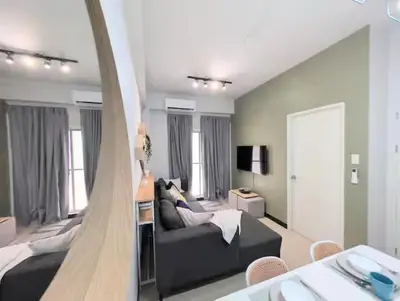 a living room with a black couch and a living room with at Cozy Garden View near Airport WFH Netflix Stay in Manila
