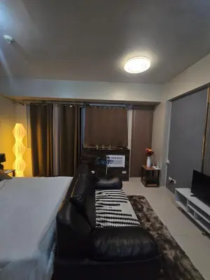 a bedroom with a bed with a couch and a television at Newport Staycation in Manila