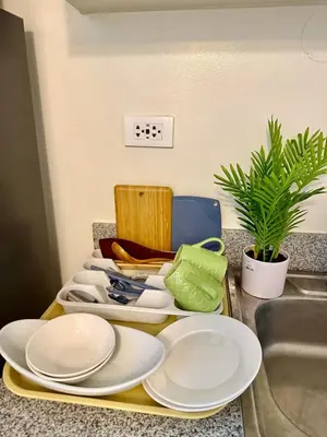 a tray with white plates on a counter next to a sink at J&A Cozy Calm Stay in Biñan