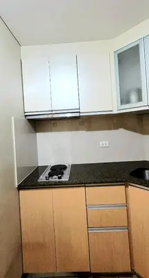 a kitchen with white cabinets and a stove top oven at Cozy Modern Studio Two Palm Tree Villas in Manila