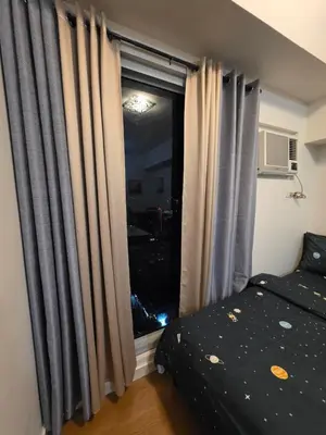 a bedroom with a bed and a window with curtains at 8 Adriatico Condominium in Manila