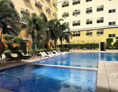 a swimming pool in a hotel with chairs and a building at J&A Cozy Calm Stay in Biñan