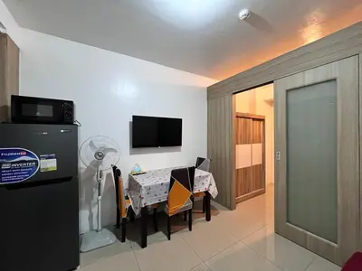 a dining room with a table and a tv and a room at Apartment in Pasay at Shore Residences in Manila
