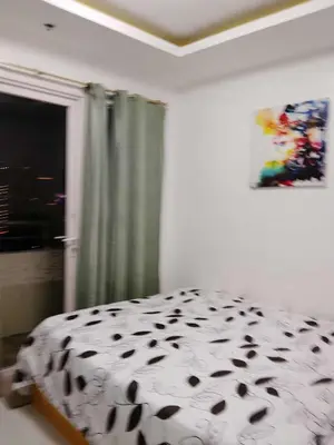 a bedroom with a black and white bed and a window at Birch tower condo for renting in Manila