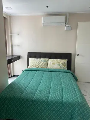a bed with a green comforter in a bedroom at Robinson's place residences tower 2 in Manila